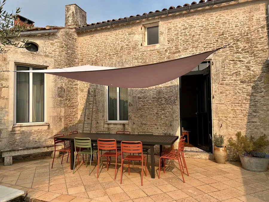 Terrasse sous voile d'ombrage contre un mur de pierre